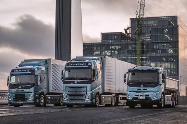 3 large commercial vehicles with dramatic industrial backdrop